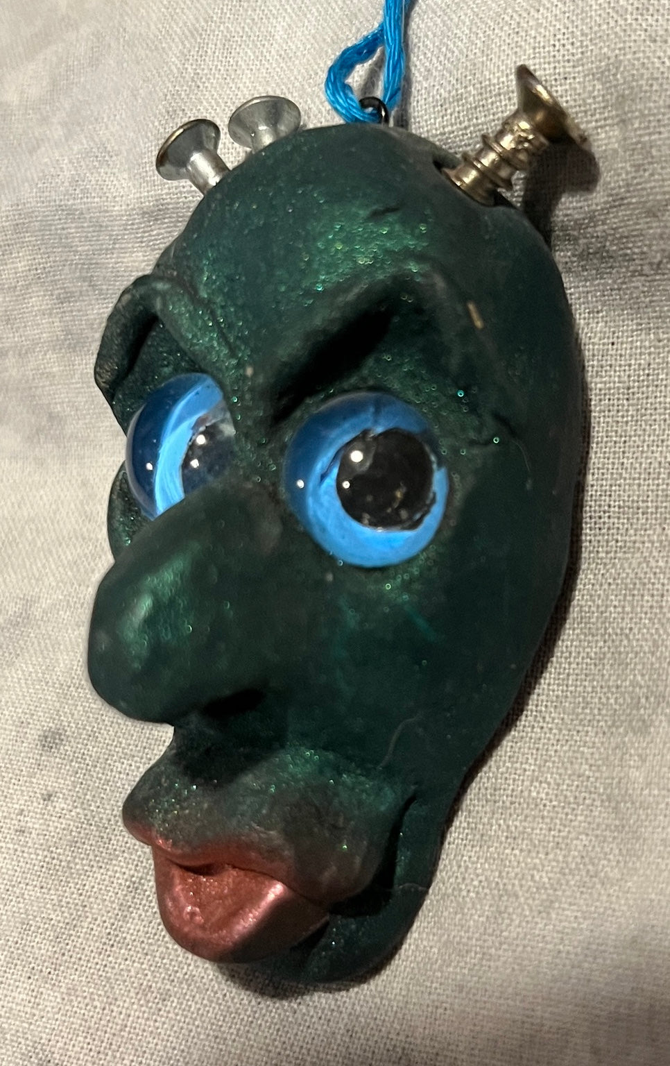 Screwball sculpted pendant, angled view showing blue glass eyes and metal screws