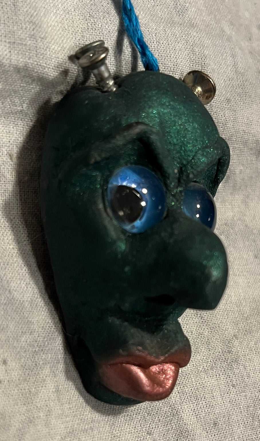 Screwball sculpted pendant, side view showing dimensional face