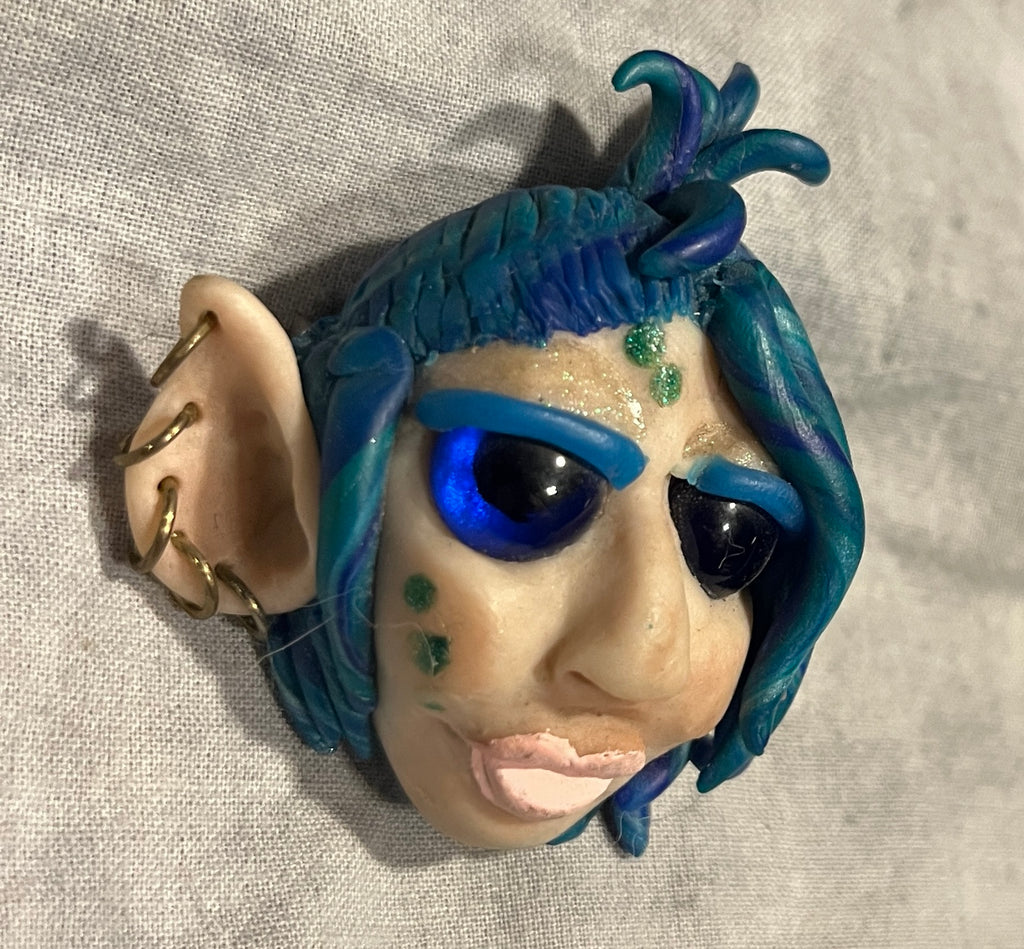 TeWana Asteria sculpted brooch, angled view showing glass eyes and facial markings