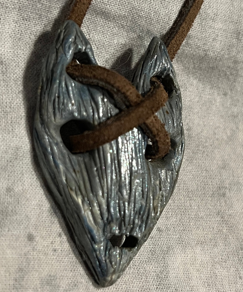 The Relic wearable curiosity, angled front view showing carved texture and brown cord